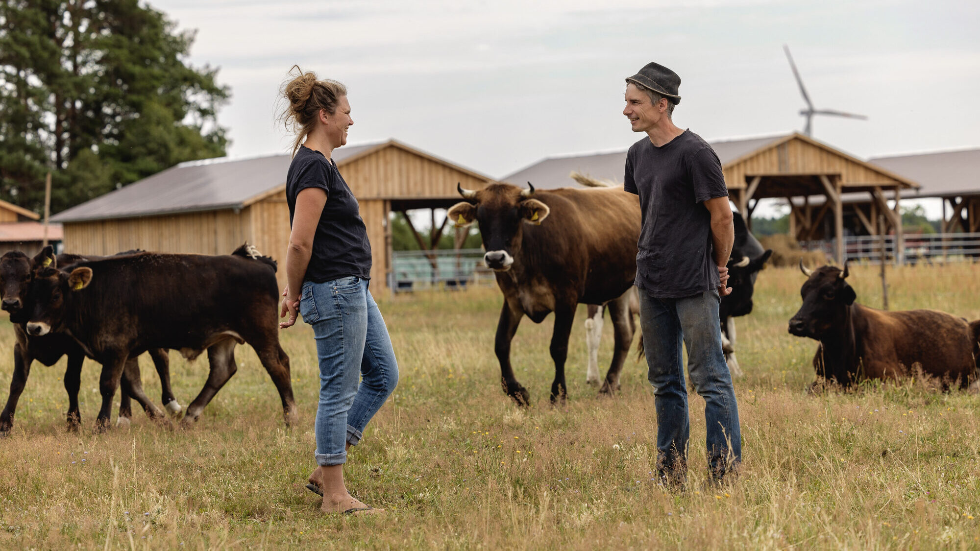 Die Junglandwirte Carolin und Arne Rost stehen auf der Weide zwischen ihren Rindern.